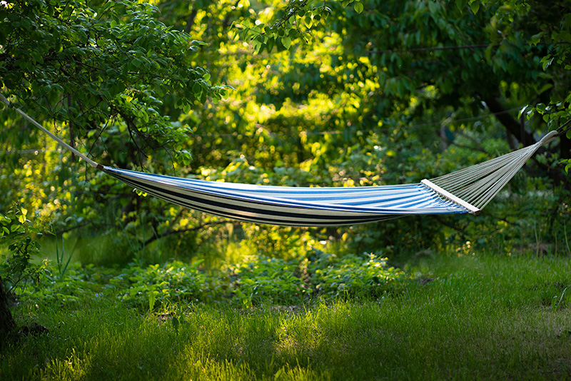 En randig hängmatta med grönska i bakgrunden.